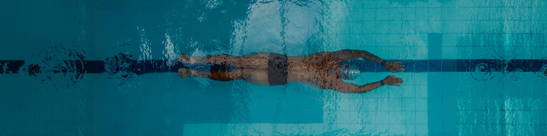 Mulher nadando na piscina com traje de natação.